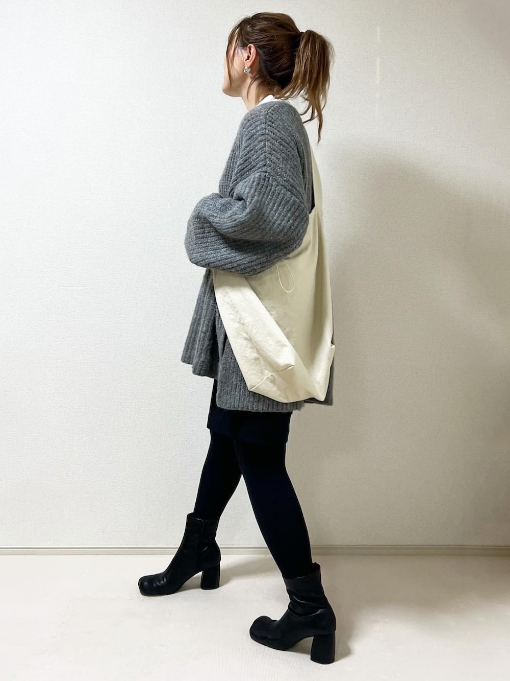 ホワイト系のショルダーバッグ、ブラック系のブーツを着用したレディースの秋コーディネートの2枚目の写真