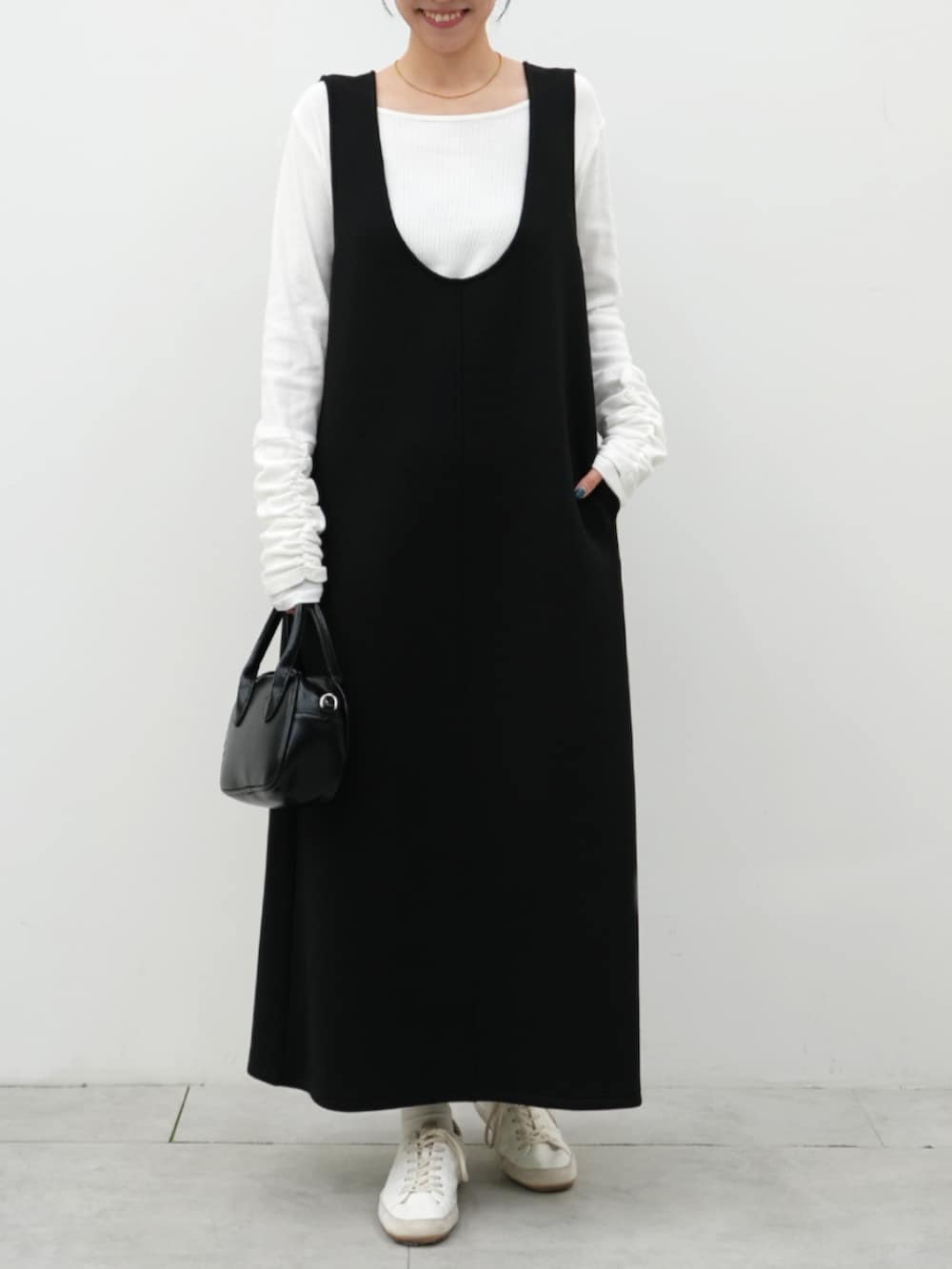 ホワイト系のTシャツ/カットソー、ブラック系のジャンパースカートを着用したレディースの冬コーディネートの4枚目の写真