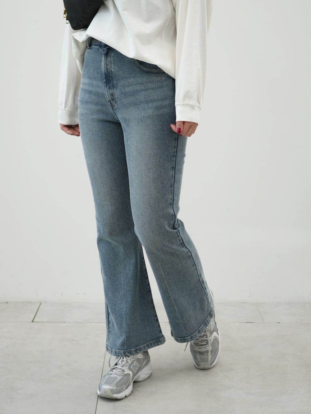 ブラック系のボディバッグ/ウエストポーチ、ベージュ系のトレンチコート、ブルー系のデニムパンツを着用したレディースの冬コーディネートの2枚目の写真