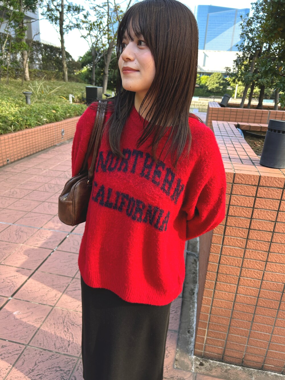 ブラック系のスカート、グレー系のニット/セーターを着用したレディースの秋コーディネートの2枚目の写真