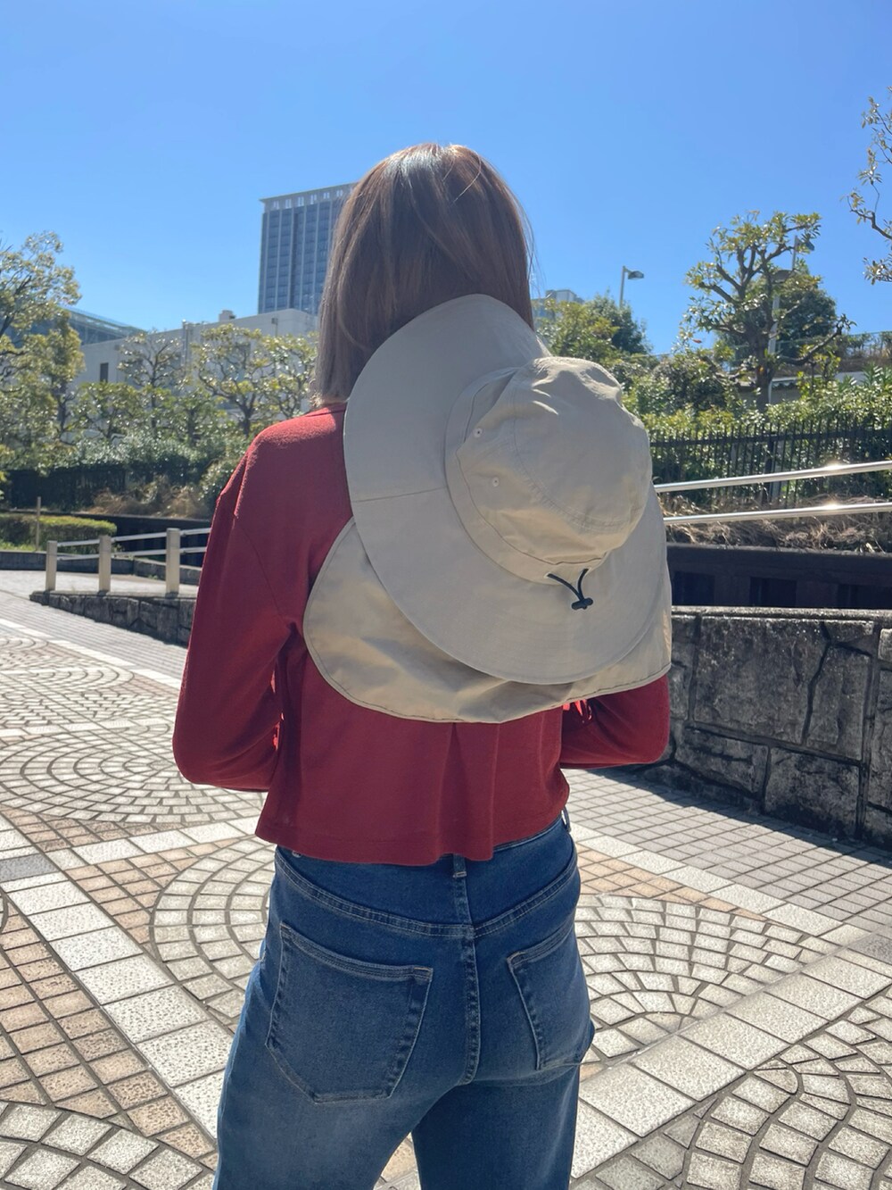 レッド系のカーディガン/ボレロ、ブルー系のデニムパンツ、ホワイト系のタンクトップを着用したレディースの春コーディネートの2枚目の写真