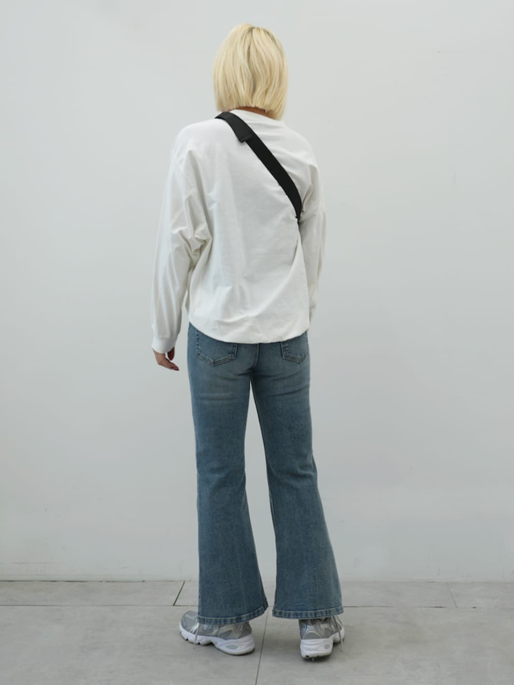 ブラック系のボディバッグ/ウエストポーチ、ベージュ系のトレンチコート、ブルー系のデニムパンツを着用したレディースの冬コーディネートの4枚目の写真