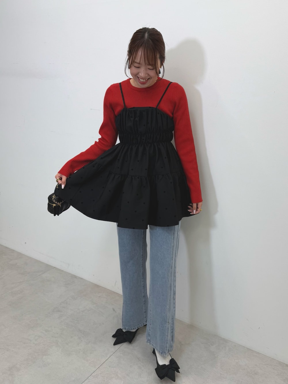 ブラック系のキャミソール、レッド系のニット/セーター、ブルー系のデニムパンツを着用したレディースの秋コーディネートの2枚目の写真