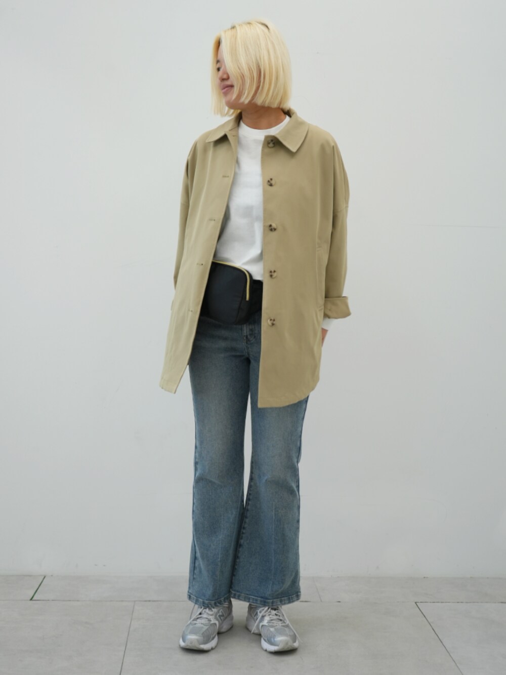 ブラック系のボディバッグ/ウエストポーチ、ベージュ系のトレンチコート、ブルー系のデニムパンツを着用したレディースの冬コーディネートの3枚目の写真