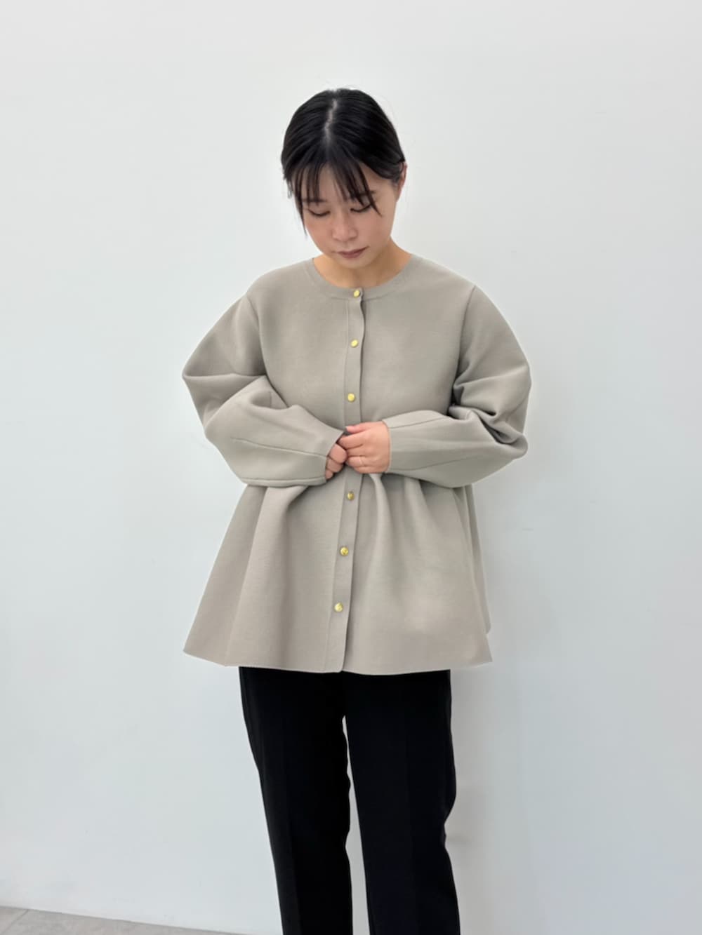 ブラック系のスラックス、ベージュ系のカーディガン/ボレロを着用したレディースの秋コーディネートの2枚目の写真