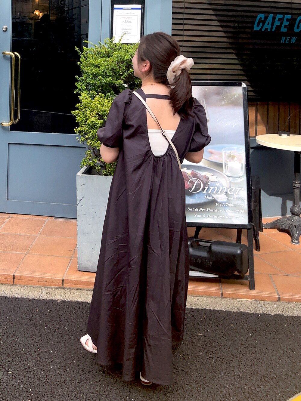 ホワイト系のショルダーバッグ、ブラック系のワンピース、ホワイト系のシューズを着用したレディースの夏コーディネートの2枚目の写真