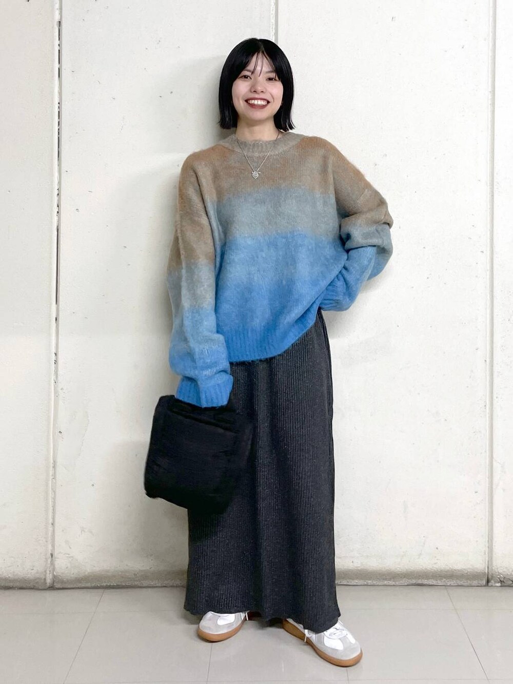 ブラック系のトートバッグ、グレー系のスカート、ブルー系のニット/セーターを着用したレディースの秋コーディネートの4枚目の写真