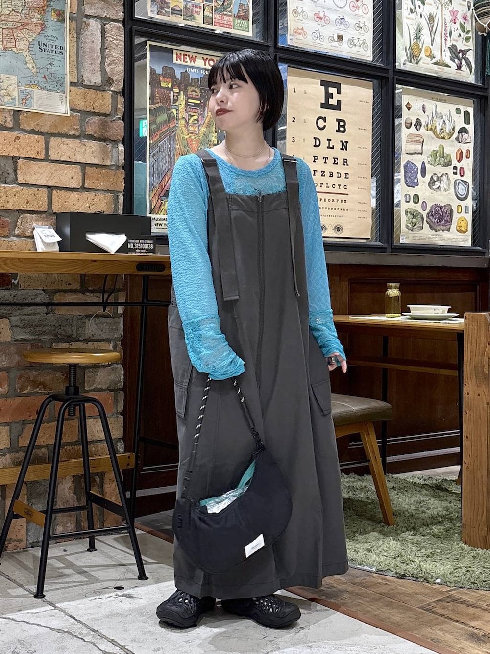 ブラック系のハンドバッグ、ブルー系のTシャツ/カットソー、グレー系のジャンパースカートを着用したレディースの夏コーディネートの6枚目の写真