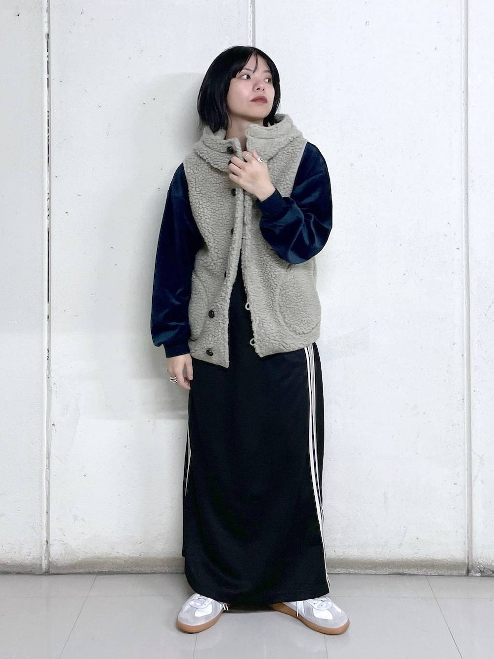 ベージュ系のベスト、ブルー系のその他トップス、ブラック系のスカートを着用したレディースの秋コーディネートの4枚目の写真