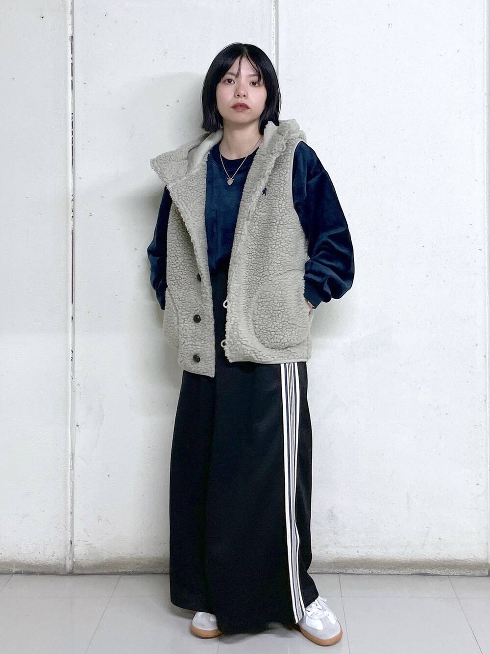 ベージュ系のベスト、ブルー系のその他トップス、ブラック系のスカートを着用したレディースの秋コーディネートの5枚目の写真