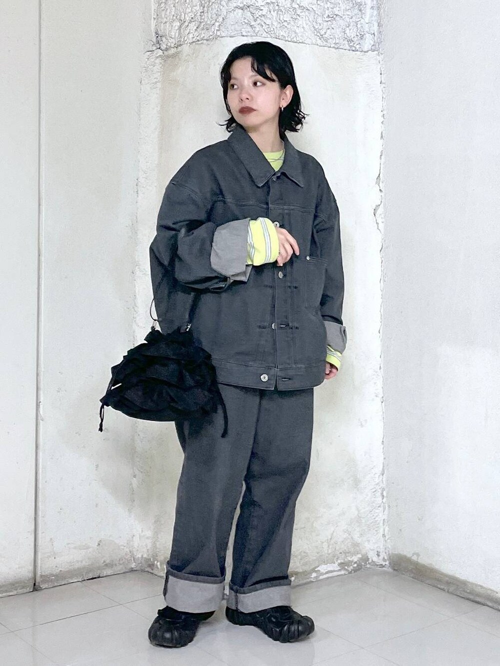 ブラック系のショルダーバッグ、イエロー系のTシャツ/カットソー、グレー系のデニムジャケットを着用したレディースの冬コーディネートの4枚目の写真