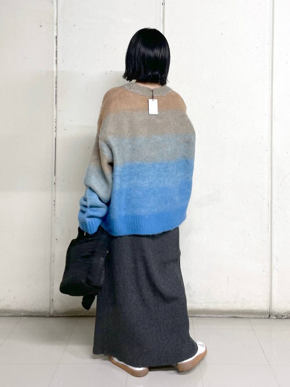 ブラック系のトートバッグ、グレー系のスカート、ブルー系のニット/セーターを着用したレディースの秋コーディネートの3枚目の写真