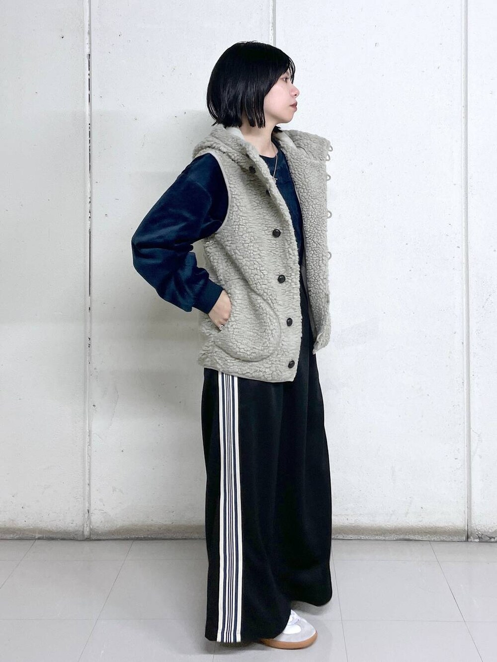 ベージュ系のベスト、ブルー系のその他トップス、ブラック系のスカートを着用したレディースの秋コーディネートの2枚目の写真