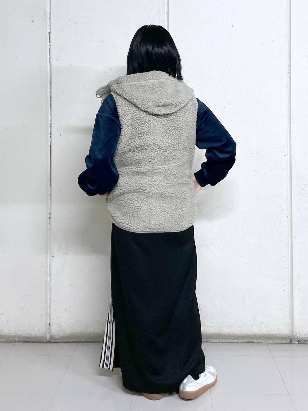 ベージュ系のベスト、ブルー系のその他トップス、ブラック系のスカートを着用したレディースの秋コーディネートの3枚目の写真