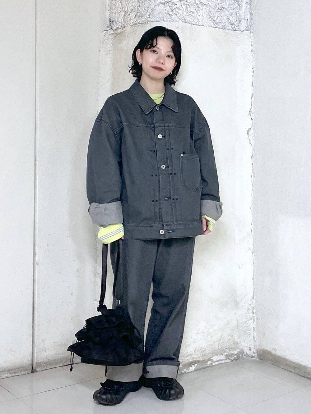 ブラック系のショルダーバッグ、イエロー系のTシャツ/カットソー、グレー系のデニムジャケットを着用したレディースの冬コーディネートの5枚目の写真