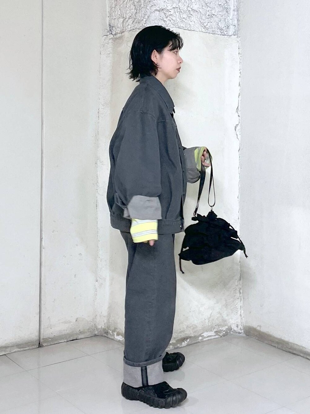 ブラック系のショルダーバッグ、イエロー系のTシャツ/カットソー、グレー系のデニムジャケットを着用したレディースの冬コーディネートの2枚目の写真