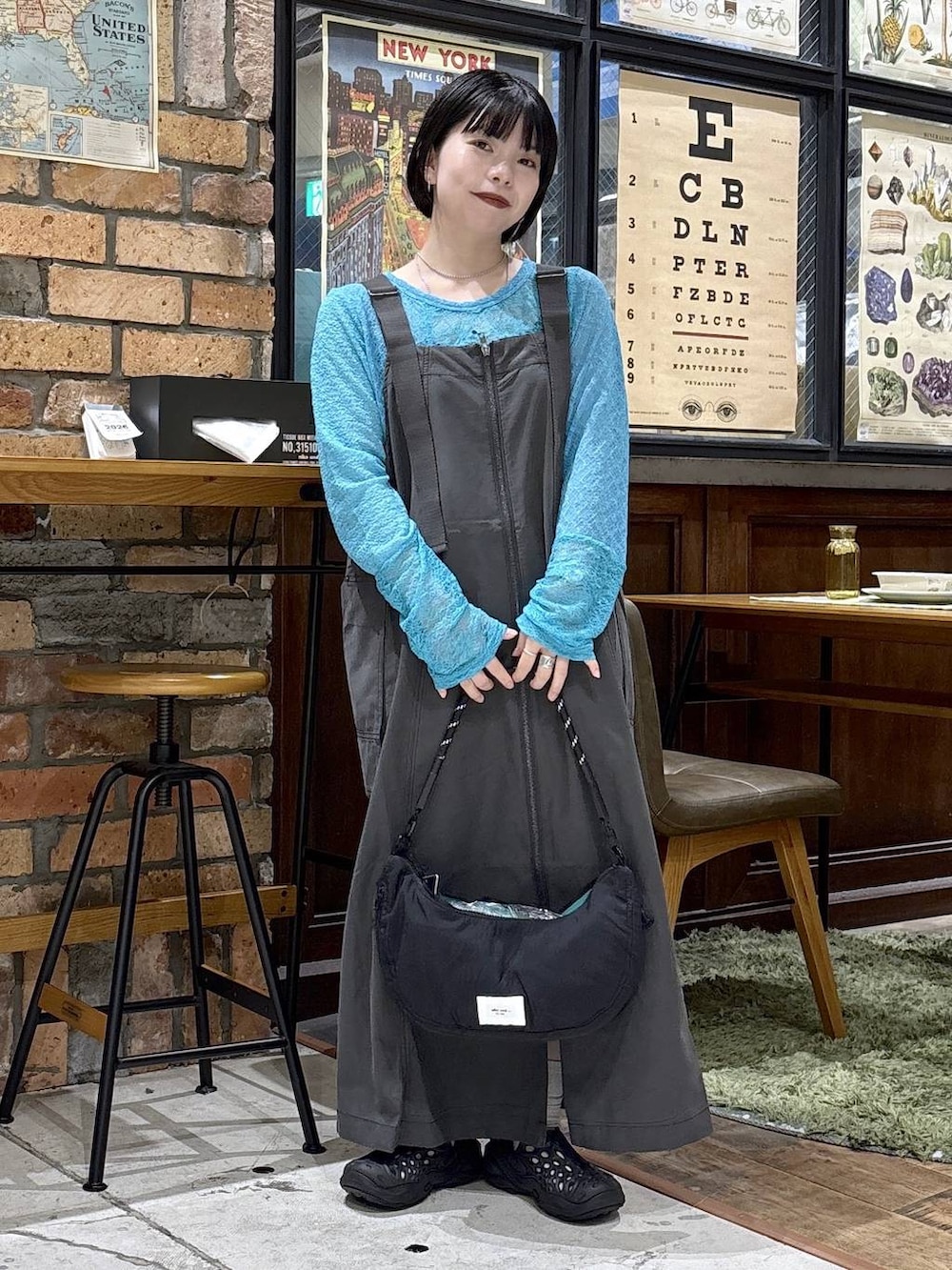 ブラック系のハンドバッグ、ブルー系のTシャツ/カットソー、グレー系のジャンパースカートを着用したレディースの夏コーディネートの4枚目の写真