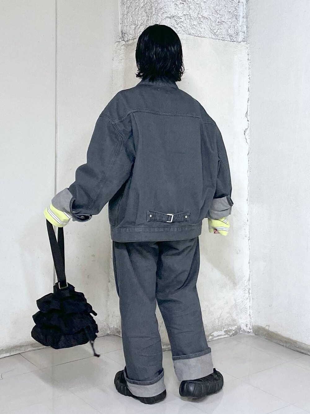 ブラック系のショルダーバッグ、イエロー系のTシャツ/カットソー、グレー系のデニムジャケットを着用したレディースの冬コーディネートの3枚目の写真