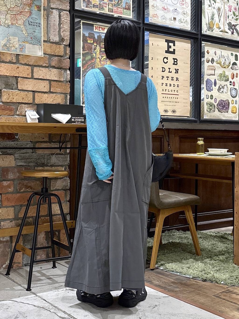 ブラック系のハンドバッグ、ブルー系のTシャツ/カットソー、グレー系のジャンパースカートを着用したレディースの夏コーディネートの3枚目の写真