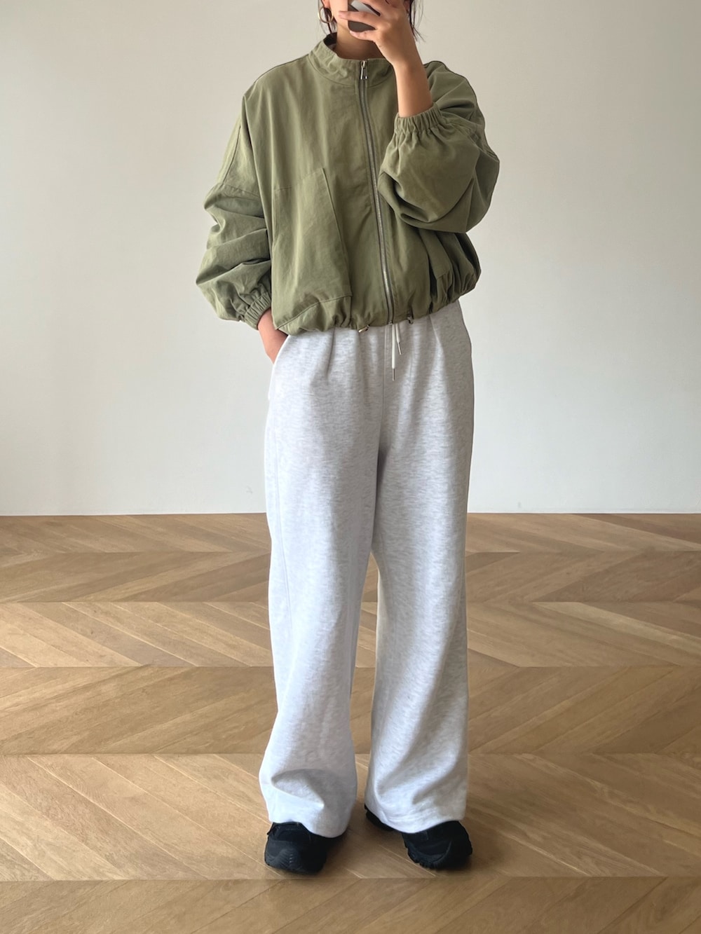 グレー系のその他パンツ、グリーン系のブルゾン、ホワイト系のキャミソールを着用したレディースの春コーディネートの2枚目の写真