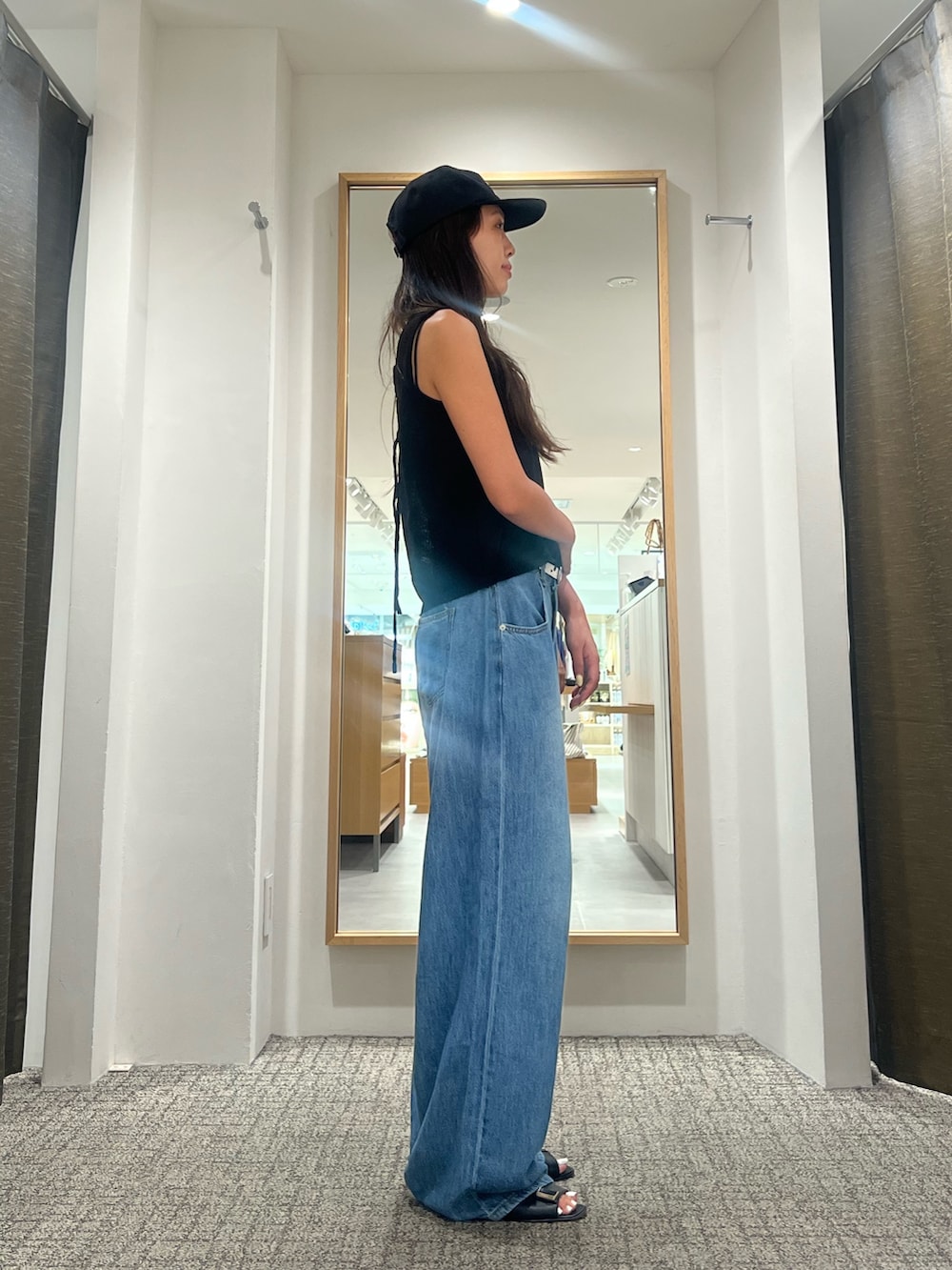 ブラック系のニット/セーター、ブルー系のデニムパンツ、ブラック系のベルトを着用したレディースの夏コーディネートの2枚目の写真