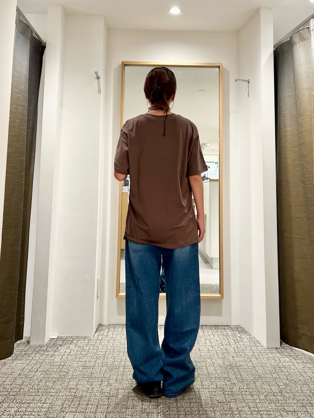 ブラック系のショルダーバッグ、ブラウン系のTシャツ/カットソー、ブルー系のデニムパンツを着用したレディースの夏コーディネートの3枚目の写真