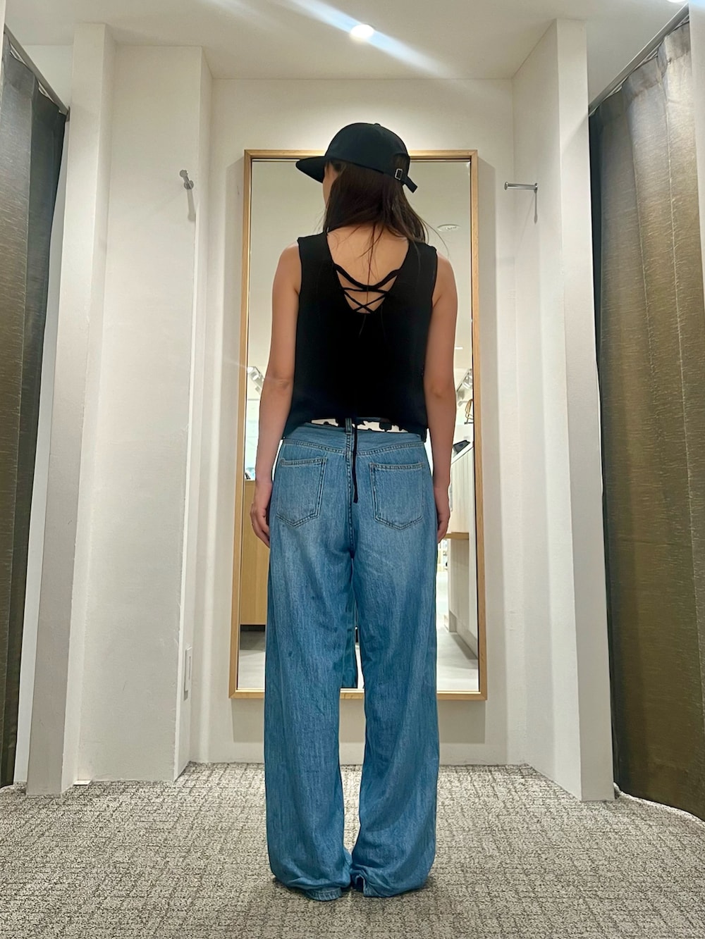 ブラック系のニット/セーター、ブルー系のデニムパンツ、ブラック系のベルトを着用したレディースの夏コーディネートの3枚目の写真
