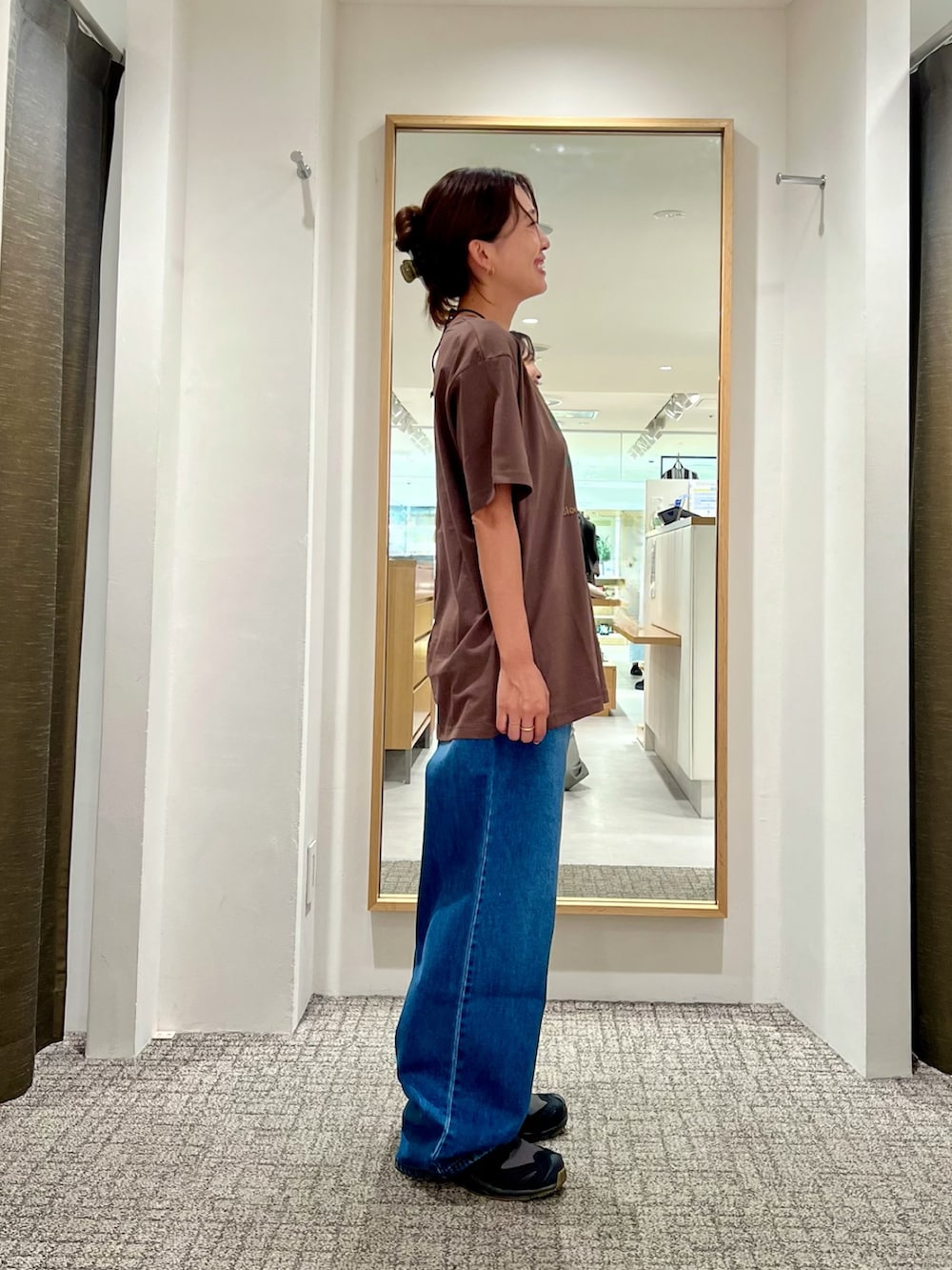 ブラック系のショルダーバッグ、ブラウン系のTシャツ/カットソー、ブルー系のデニムパンツを着用したレディースの夏コーディネートの2枚目の写真