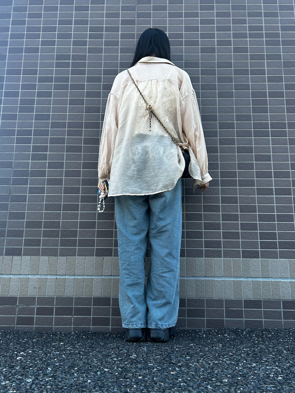 ブラック系のスニーカー、ブルー系のデニムパンツ、ベージュ系のシャツ/ブラウスを着用したレディースの春コーディネートの2枚目の写真