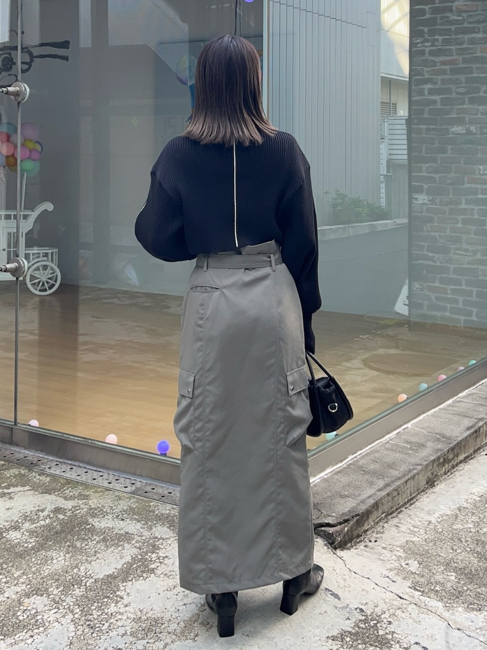 ブラック系のニット/セーター、グレー系のスカート、ブラック系のショルダーバッグを着用したレディースの冬コーディネートの4枚目の写真