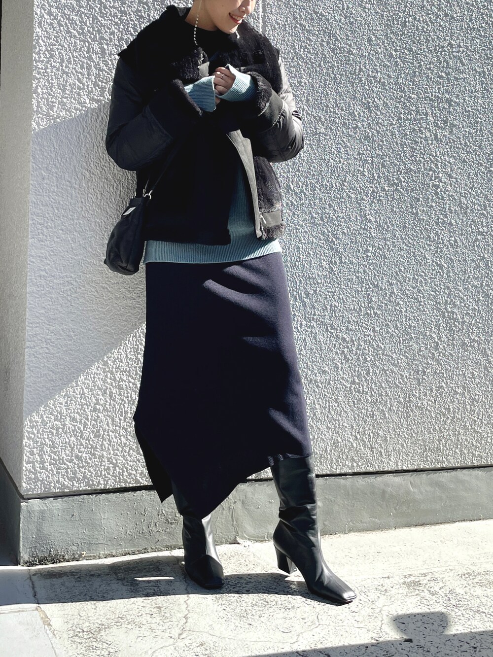 ブラック系のダウンジャケット/コート、ブルー系のニット/セーター、ブルー系のワンピースを着用したレディースの春コーディネートの2枚目の写真