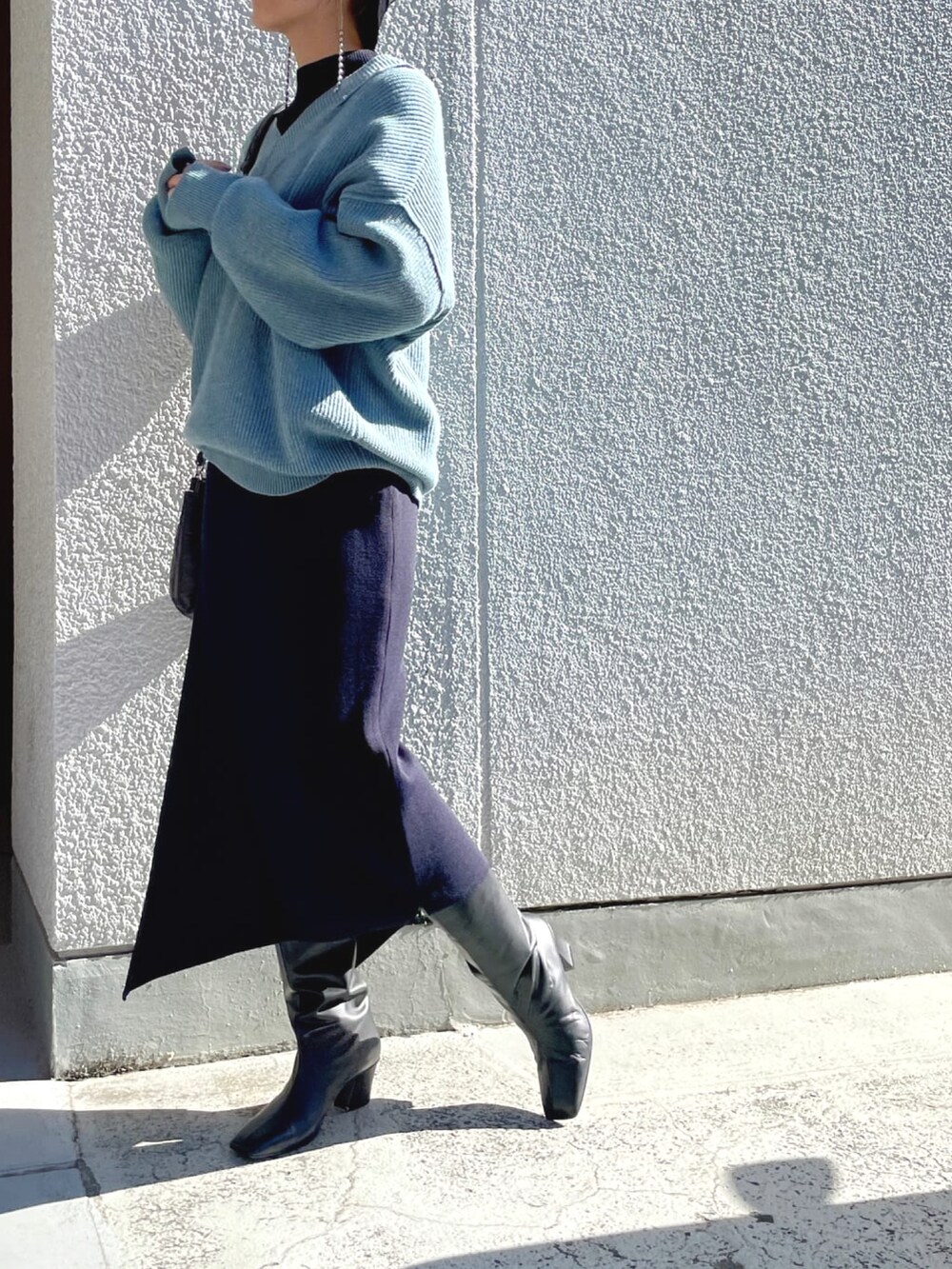 ブルー系のニット/セーター、ブルー系のワンピース、ブラック系のショルダーバッグを着用したレディースの春コーディネートの2枚目の写真