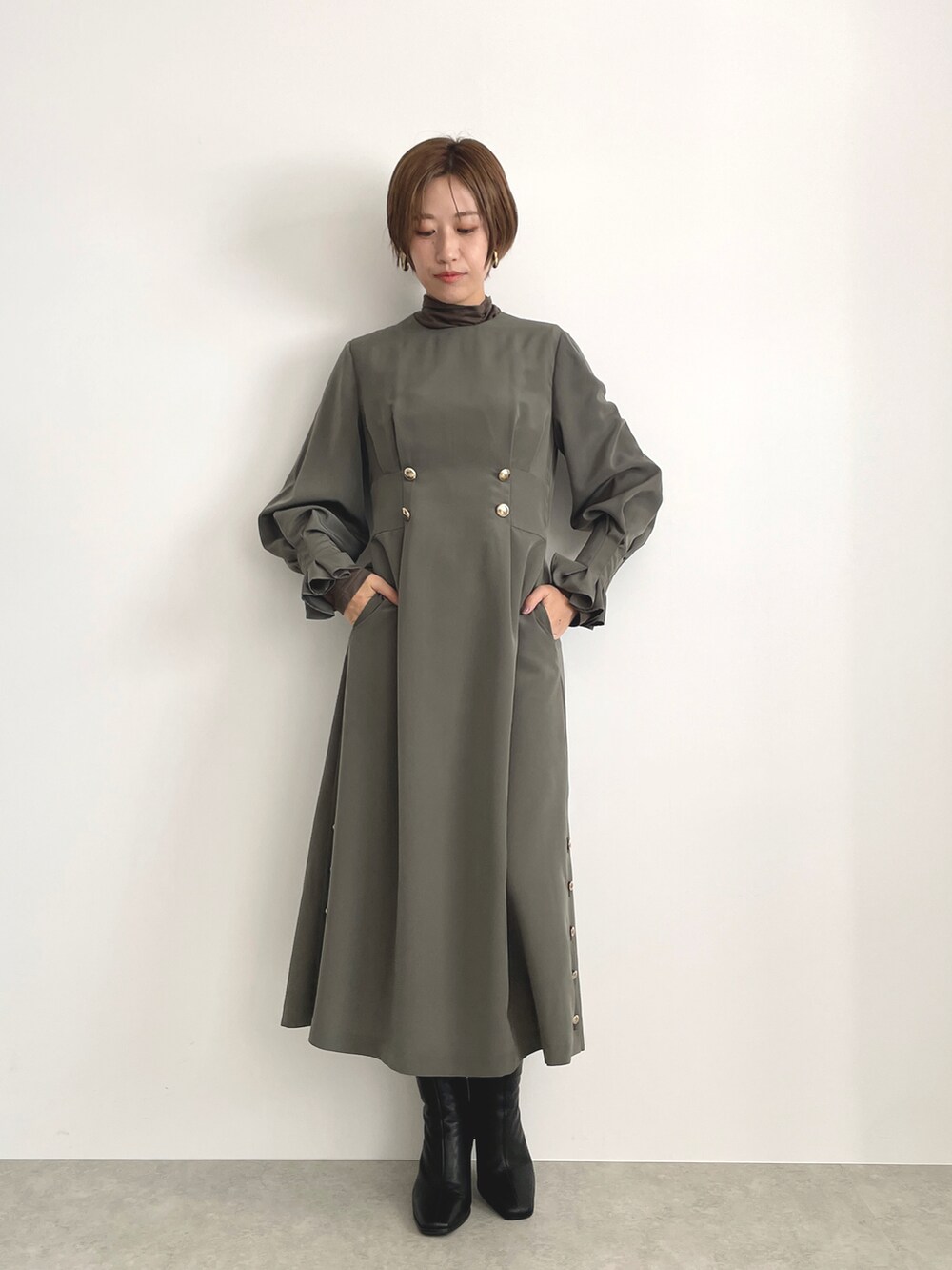 グリーン系のワンピース、ブラック系のバッグを着用したレディースの冬コーディネートの2枚目の写真