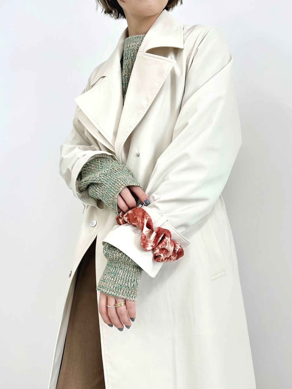 ホワイト系のトレンチコート、グリーン系のニット/セーター、ベージュ系のその他パンツを着用したレディースの冬コーディネートの3枚目の写真