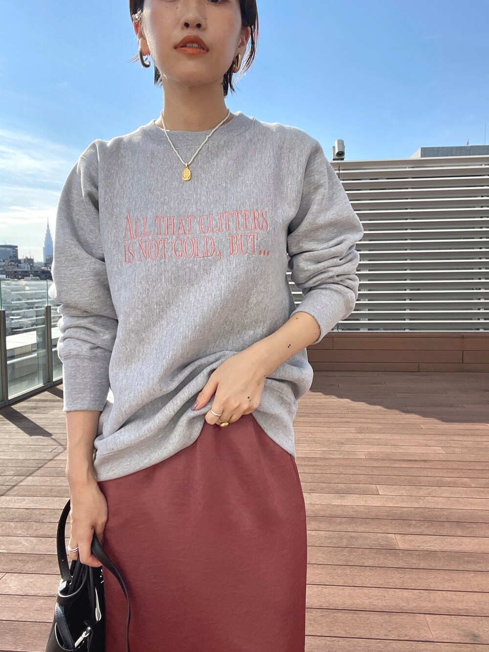 ブラウン系のスカート、ブラック系のその他シューズ、ブラック系のハンドバッグを着用したレディースの秋コーディネートの3枚目の写真