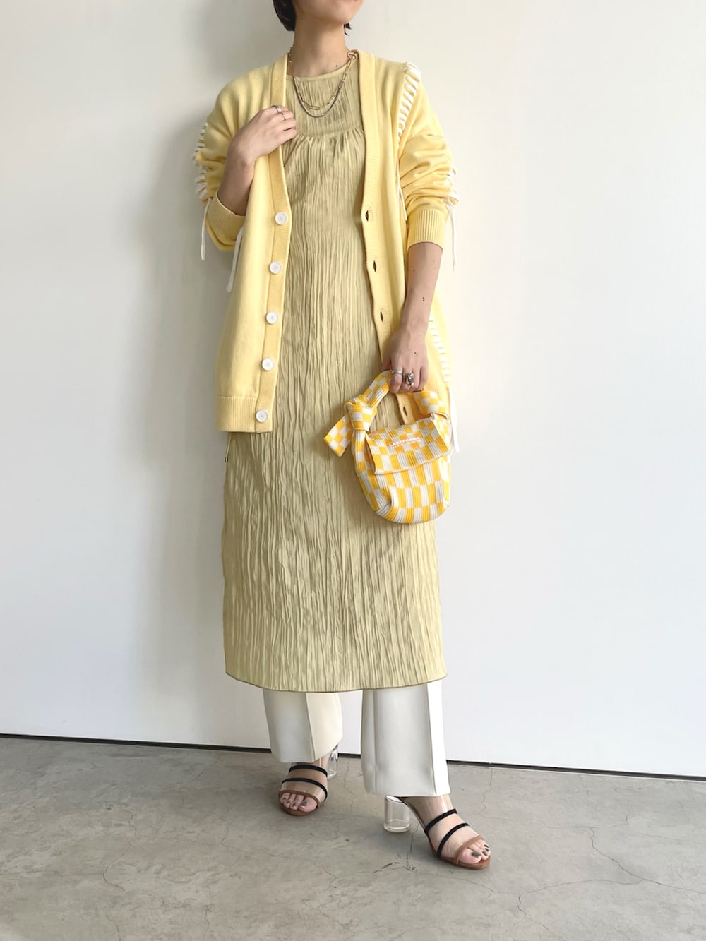 イエロー系のカーディガン/ボレロ、イエロー系のワンピース、イエロー系のバッグを着用したレディースの春コーディネートの2枚目の写真