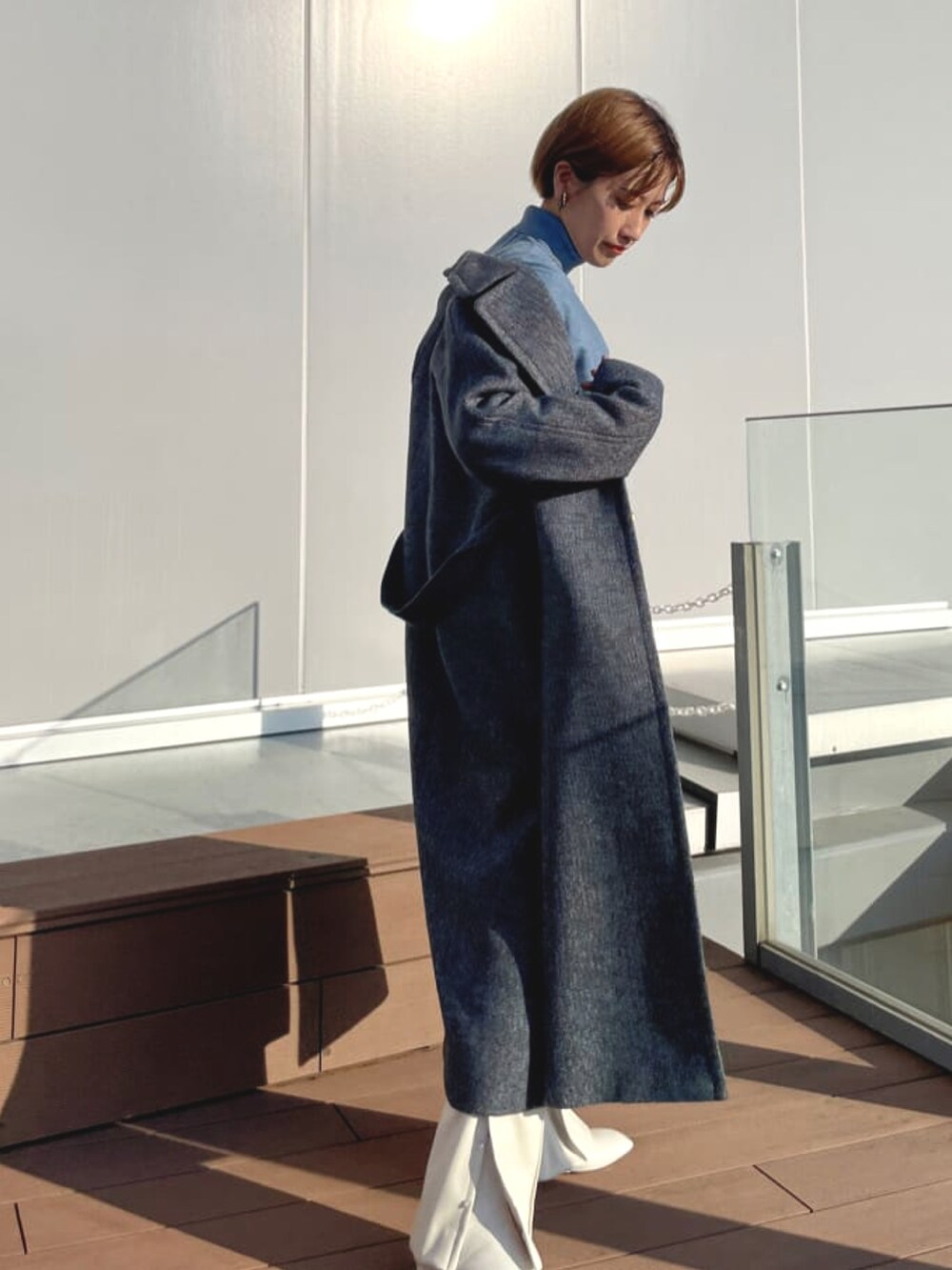 ブルー系のチェスターコート、ブルー系のニット/セーター、ホワイト系のその他パンツを着用したレディースの春コーディネートの2枚目の写真