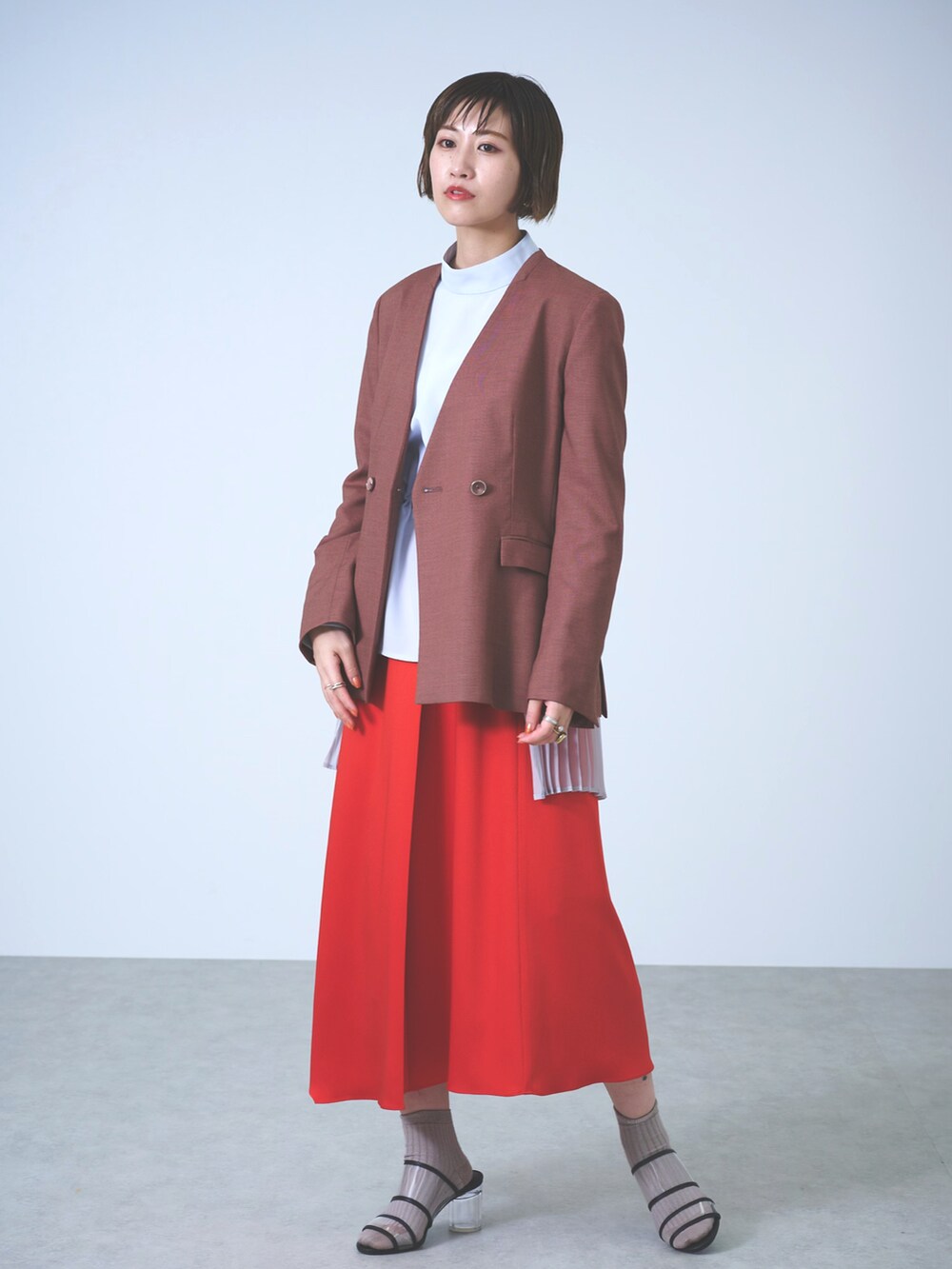 ブラウン系のノーカラージャケット、ブルー系のシャツ/ブラウス、レッド系のスカートを着用したレディースの春コーディネートの3枚目の写真