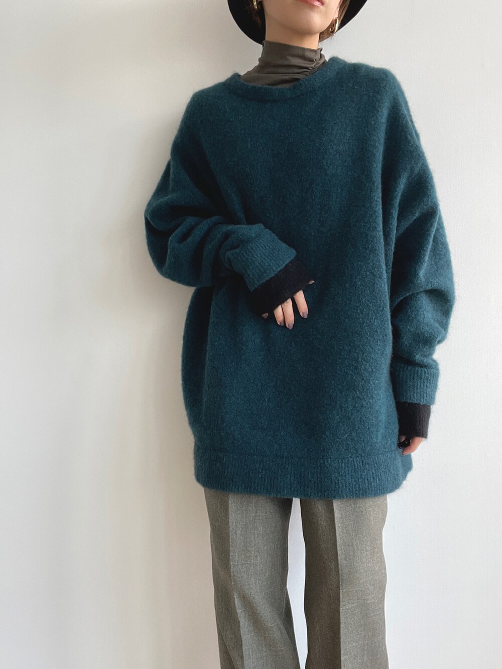 グリーン系のニット/セーター、グリーン系のその他トップス、グレー系のスラックスを着用したレディースの春コーディネートの3枚目の写真