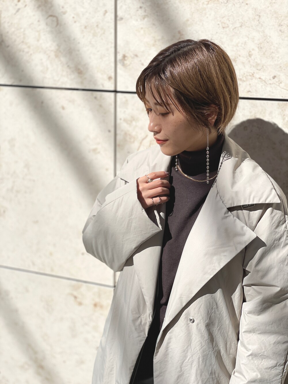 ブラウン系のニット/セーター、ベージュ系のダウンジャケット/コート、グリーン系のその他パンツを着用したレディースの春コーディネートの4枚目の写真