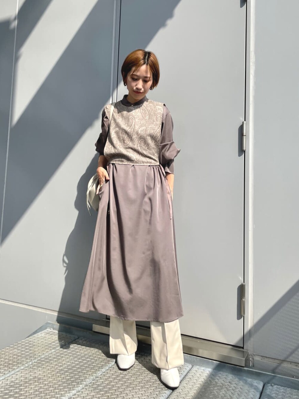 グリーン系のトレンチコート、グレー系のワンピース、ホワイト系のその他パンツを着用したレディースの冬コーディネートの2枚目の写真