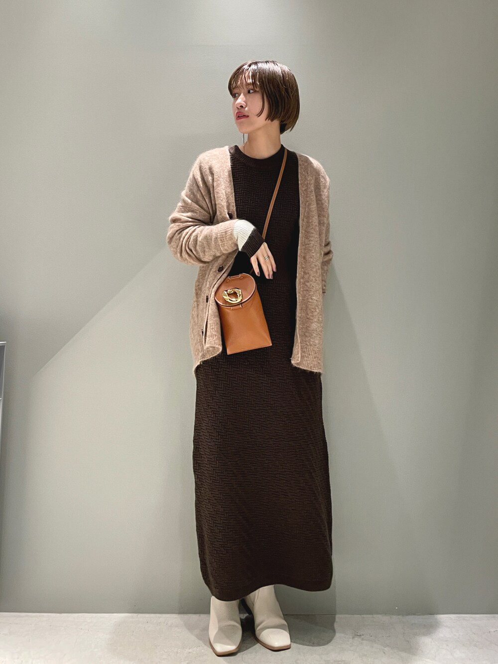 ベージュ系のカーディガン/ボレロ、ブラウン系のワンピース、ブラウン系のショルダーバッグを着用したレディースの春コーディネートの2枚目の写真