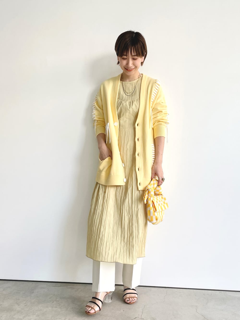 イエロー系のカーディガン/ボレロ、イエロー系のワンピース、イエロー系のバッグを着用したレディースの春コーディネートの3枚目の写真