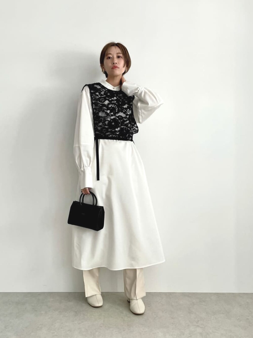 ホワイト系のワンピース、ブラック系のバッグ、ホワイト系のその他パンツを着用したレディースの冬コーディネートの2枚目の写真