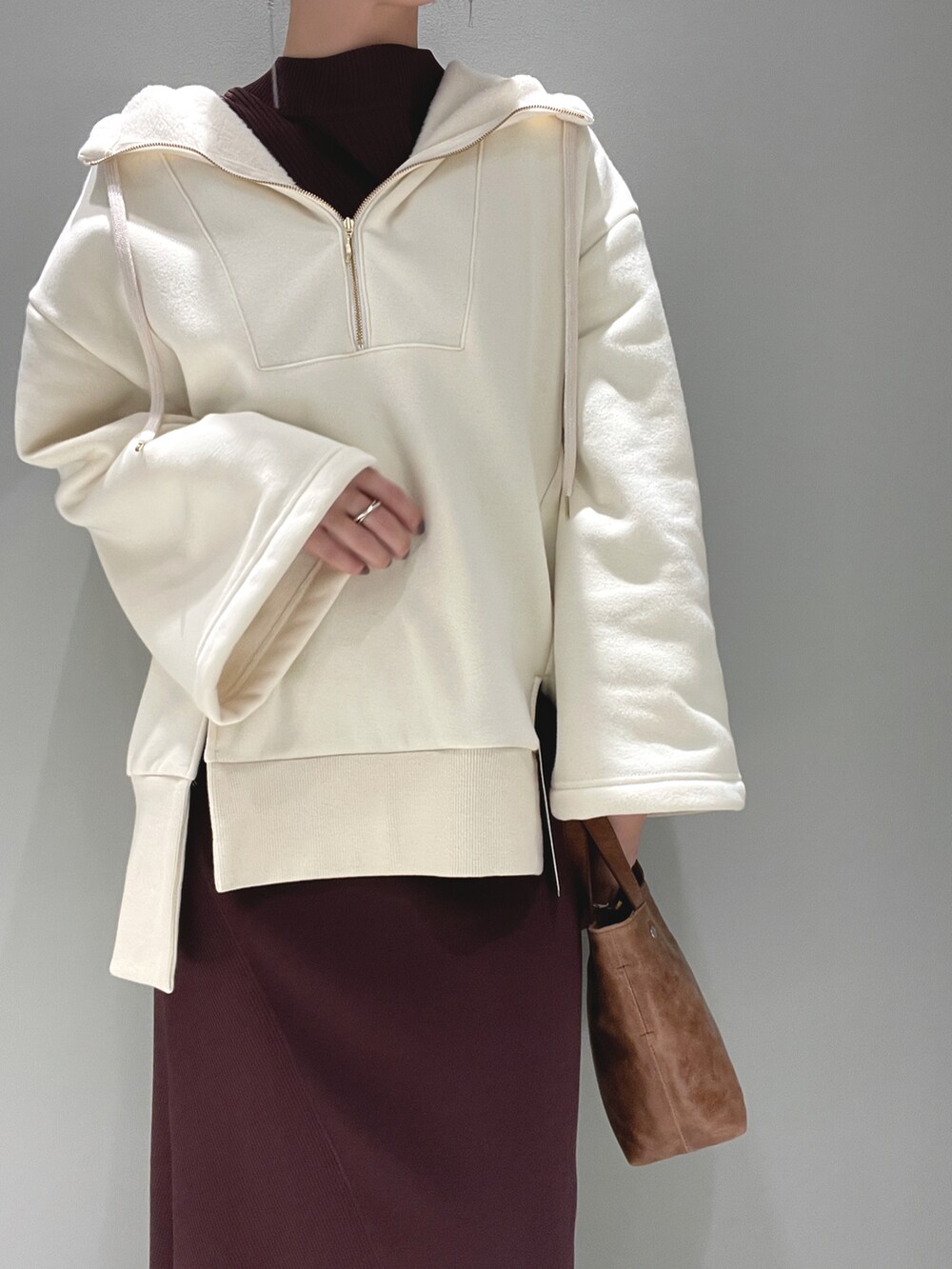 ホワイト系のパーカー、ブラウン系のワンピース/ドレス、ベージュ系のスニーカーを着用したレディースの春コーディネートの3枚目の写真