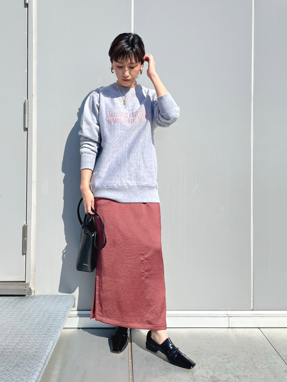 ブラウン系のスカート、ブラック系のその他シューズ、ブラック系のハンドバッグを着用したレディースの秋コーディネートの2枚目の写真