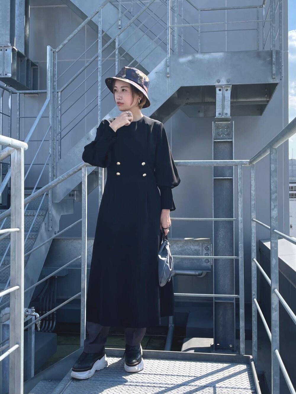 ブラック系のワンピース、ブラウン系のスラックス、グレー系のハンドバッグを着用したレディースの冬コーディネートの2枚目の写真