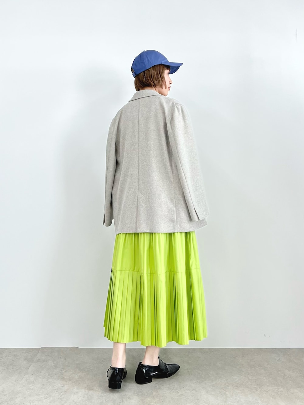 ベージュ系のテーラードジャケット、ブラック系のニット/セーター、グリーン系のスカートを着用したレディースの春コーディネートの2枚目の写真