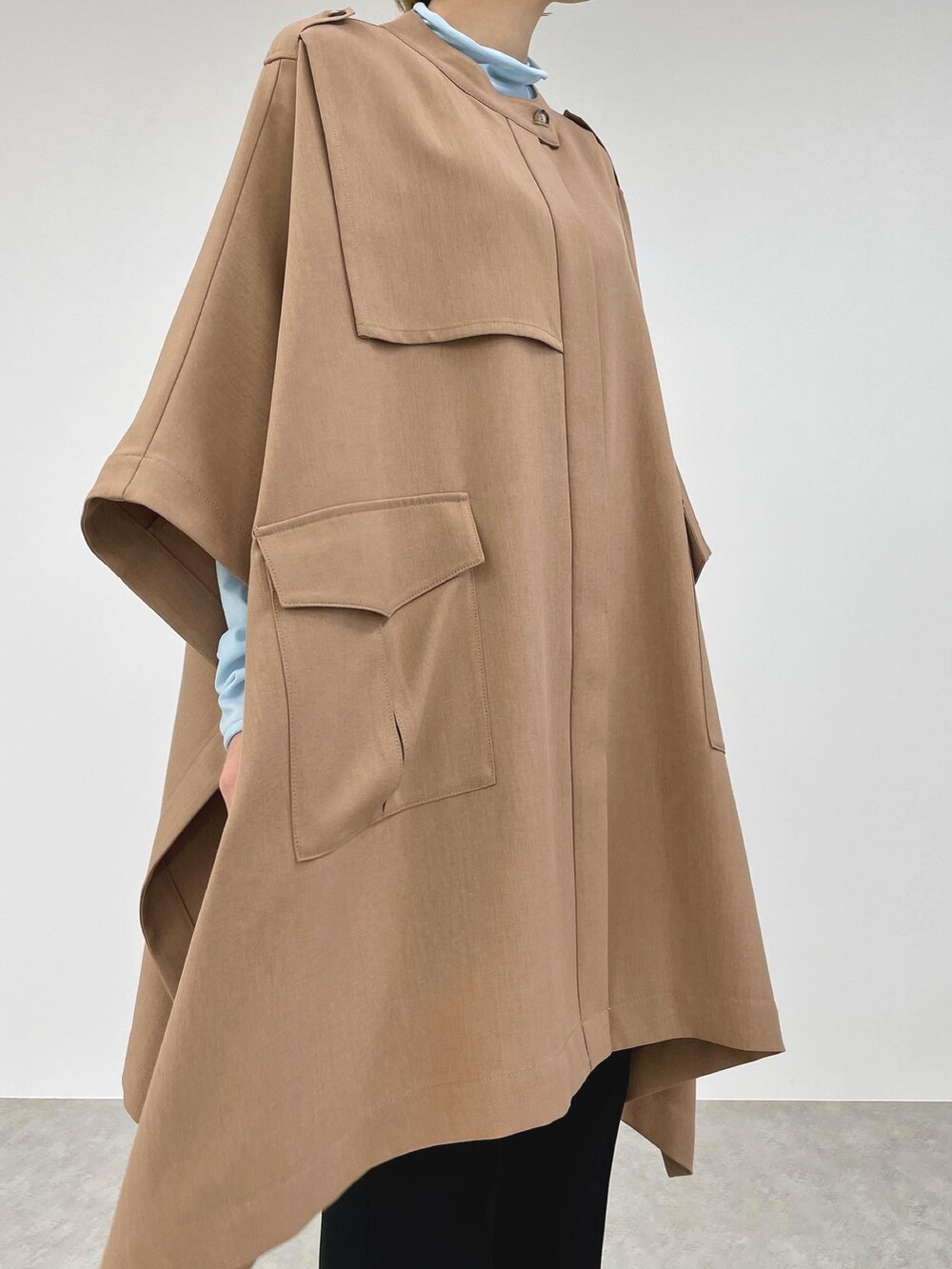 ベージュ系のポンチョ、ブルー系のその他トップス、ブラック系のその他パンツを着用したレディースの春コーディネートの2枚目の写真