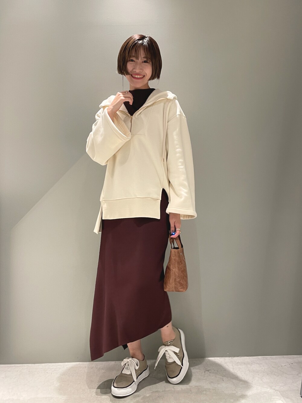 ホワイト系のパーカー、ブラウン系のワンピース/ドレス、ベージュ系のスニーカーを着用したレディースの春コーディネートの2枚目の写真